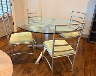 Round glass-top dining table with chrome base and 4 chairs