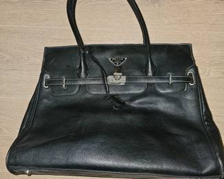 A black pebbled leather Prada handbag with silver hardware and clasp closure.