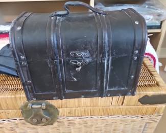 A dark-colored decorative chest with metal banding and a leather handle.