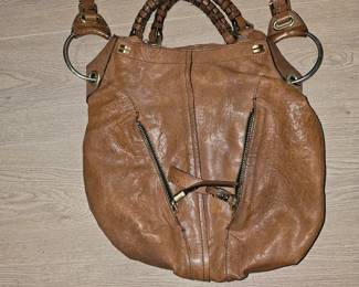 This is a brown distressed leather Oryany hobo handbag with braided handles.