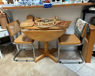 Drop leaf pedestal table with two cane chairs (one seat is damaged)