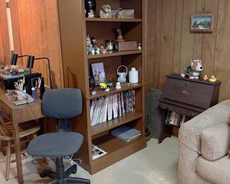 In this photo you can see the office chair, a tall bookcase, the corner of a sofa, and a small secrretary's desk.