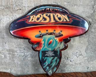 Boston commemorative plaque celebrating the sale of more than one million copies of the LP “Boston.” The design replicates the iconic album cover, featuring a UFO motif with vibrant colors and a mounted metal dedication plate. Includes documentation verifying authenticity. Constructed from wood and metal materials, with visible mounting hardware on the reverse side. Accompanied with a certificate of authenticity.