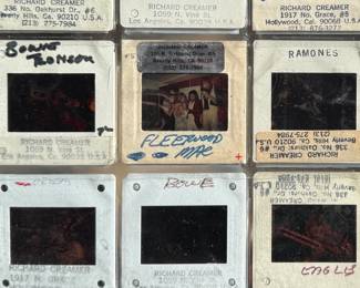 Vintage 35mm slides primarily organized in a transparent holder. Each slide features labels with the name “Richard Creamer” and addresses in Beverly Hills and Los Angeles, CA. Subjects documented include notable music acts such as KISS, Ramones, Fleetwood Mac, and others. Handwritten annotations accompany several slides. Great condition for archival or display purposes.