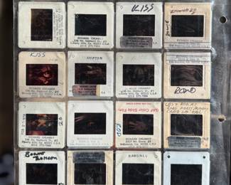 Vintage 35mm slides primarily organized in a transparent holder. Each slide features labels with the name “Richard Creamer” and addresses in Beverly Hills and Los Angeles, CA. Subjects documented include notable music acts such as KISS, Ramones, Fleetwood Mac, and others. Handwritten annotations accompany several slides. Great condition for archival or display purposes.