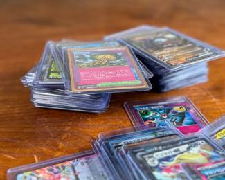 Lot consists of assorted Japanese Pokémon trading cards with holographic and full-art designs. Cards are stored in individual sleeves or protective cases.