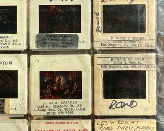 Vintage 35mm slides primarily organized in a transparent holder. Each slide features labels with the name “Richard Creamer” and addresses in Beverly Hills and Los Angeles, CA. Subjects documented include notable music acts such as KISS, Ramones, Fleetwood Mac, and others. Handwritten annotations accompany several slides. Great condition for archival or display purposes.