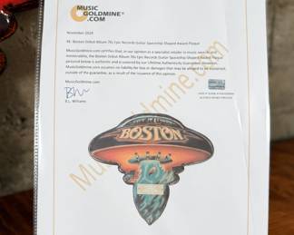 Boston commemorative plaque celebrating the sale of more than one million copies of the LP “Boston.” The design replicates the iconic album cover, featuring a UFO motif with vibrant colors and a mounted metal dedication plate. Includes documentation verifying authenticity. Constructed from wood and metal materials, with visible mounting hardware on the reverse side. Accompanied with a certificate of authenticity.