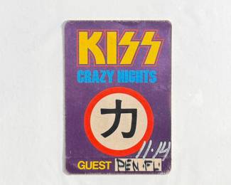 A Kiss ‘Crazy Nights’ tour guest pass badge featuring purple and yellow graphics with Japanese kanji symbol at the center. Includes handwritten details and signed area.