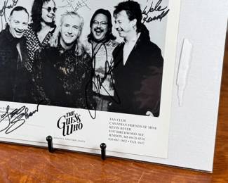 Black-and-white promotional photograph of The Guess Who, measuring 8” H x 10” W. Features five signatures on the front. Includes names of former members and band details at the bottom of the image. Housed in a protective sleeve.