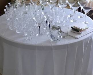 Clear wine and drinking glasses of varying heights and styles including genuine crystal.
