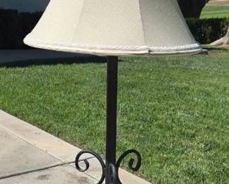 Wrought iron table lamp with elegant scrollwork, topped by a large cream-colored drum shade.