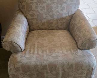 Upholstered club chair with a soft, rounded back and rolled arms in a traditional style fabric featuring a subtle paisley/leaf pattern in muted beige and rose tones. The seat is wide and deep with a low profile, and the chair sits on short turned wooden feet, giving it a comfortable, classic living‑room look.