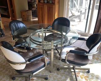 Custom glass top table with 4 rolling, swivel chairs covered in genuine cowhide. Very comfortable.