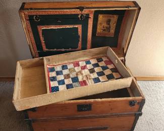Camel back trunk with lithograph insert and tray. Includes a baby quilt and a couple clothes