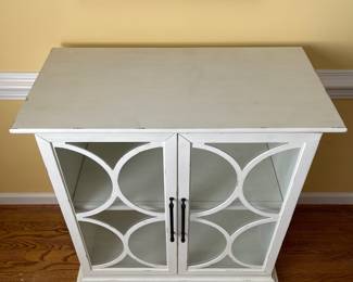 D22 - $350. Haverty’s Edisto accent cabinet. Great condition and solid construction. Distressed white cabinet with glass doors and one shelf. Has a small hole cut in the back to use for electronics. Measures 36” wide  x18” deep x 39” tall. 