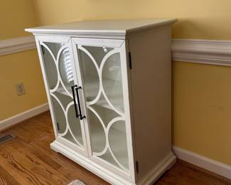D22 - $350. Haverty’s Edisto accent cabinet. Great condition and solid construction. Distressed white cabinet with glass doors and one shelf. Has a small hole cut in the back to use for electronics. Measures 36” wide  x18” deep x 39” tall. 