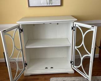 D22 - $350. Haverty’s Edisto accent cabinet. Great condition and solid construction. Distressed white cabinet with glass doors and one shelf. Has a small hole cut in the back to use for electronics. Measures 36” wide  x18” deep x 39” tall. 