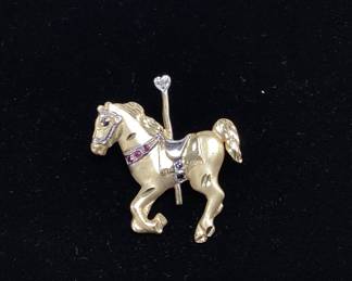 14k, ruby, saphire, diamond pendant 3.6 grams This 14k gold two tone carousel horse features pendant hook and brooch pin with satin and polished gold. Comes with music gift box