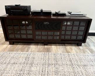 Wood media console with sliding glass paned doors and shown with stereo and video componets 
