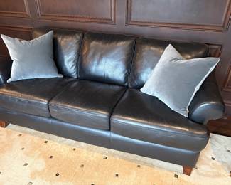 Black "pebbled" leather 3-cushion couch with attached back cushions and shown with grey velvet pillows with down inserts