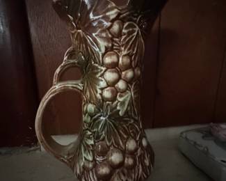 Nelson McCoy pottery pitcher featuring a grapevine and leaves motif in a green and brown glaze. Produced between the 1930's and 1950's.