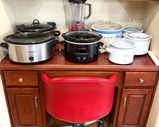 Kitchen essentials such as crockpots, blender and red leather rolling chair.