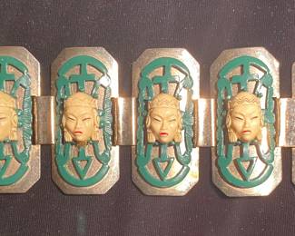 a vintage 1950s Serlo Sellini Asian-themed bracelet featuring carved plastic or resin faces and green enamel panels set in gold-tone metal