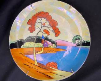  a decorative plate featuring a scenic landscape, likely produced in Japan during the 1920s or 1930s as part of the Art Deco lusterware movement