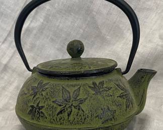 an Iwachu Japanese Cast Iron Tetsubin Teapot featuring a green maple leaf design