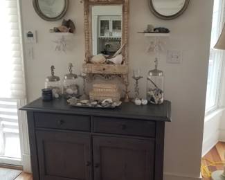 Elegant two-drawer cupboard; ornate wall miror; artful decor