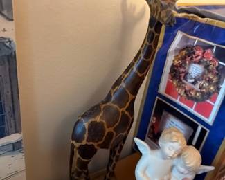 Carved wood giraffe sculpture and Lladro-style porcelain angel