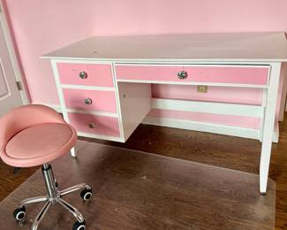 A pretty pink and white desk with rolling chair.