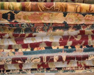 A collection of rugs stacked and organized by size