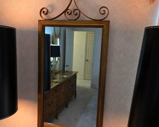 vintage gold-framed wall mirror featuring decorative wrought iron scrollwork at the top