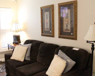 Brown microfiber sofa, plush 3 cushion couch, upholstered living room sofa, oversized comfortable couch, neutral living room furniture, family room seating, soft fabric couch, traditional style sofa, casual living room set Decorative throw pillows, neutral accent pillows, textured pillows, farmhouse style pillows, cream and blue pillows Leather ottoman, brown leather ottoman, upholstered ottoman, coffee table ottoman, footrest Framed wall art set, pineapple artwork, tropical wall décor, gold ornate frames, traditional wall art, matching art set, vintage style prints Table lamps, floor lamp, accent lighting, traditional lamps, ceramic lamp base, neutral lamp shades End tables, side tables, wood accent tables, living room tables Area rug, patterned rug, neutral rug, living room rug Home décor, traditional décor, transitional style, cozy living room setup, estate sale furniture, household furnishings