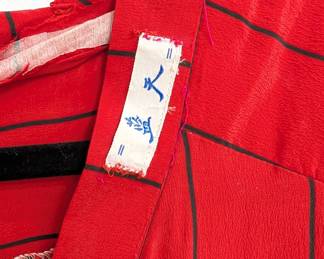 Closeup of the red silk dress with black pinstripes, button front and short sleeves