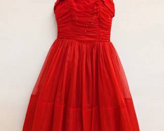 A vintage 1950s red chiffon cocktail dress with spaghetti straps and a tea-length skirt, the fitted and ruched bodice decorated with rhinestones.