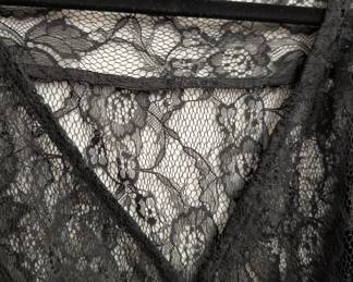 Closeup of H&M black lace blouse with short ruffled sleeves, button front closure and a black ribbon belt