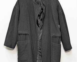 An oversized black wool coat with waist tie and large front pockets, similar to a kimono-style wrap coat; made in the USA.