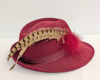 A vintage burgundy wool fedora hat with pheasant feathers