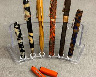 A selection of antique and vintage fountain pens and mechanical pencils including a Waterman's Red Ripple, a Cavalier butterscotch marble celluloid body pen with gold-plated clip,  a vintage "black pearl" celluloid body fountain pen and mechanical pencil combo, a 1930s-40s vintage Epenco fountain pen with a distinctive "lapis and bronze" marbled celluloid finish, and an antique Sheaffer Flat Top fountain pen crafted from black chased hard rubber and with a wide gold-filled or gold-plated band on the cap with calligraphic style inscription of J.R. 1918. 