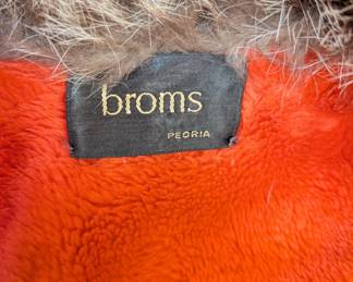 Closeup of the fabulous 1960s Bonnie Cashin for Sills orange leather & raccoon fur coat, two gold buckles across the bust and the waist; lined with faux orange shearling, with Broms label (Broms Furs, Peoria, Illinois)