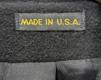 Closeup of the oversized black wool coat with waist tie and large front pockets, similar to a kimono-style wrap coat; made in the USA.