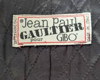 Closeup of 1980s vintage Jean Paul Gaultier Pour Gibo red wool suit featuring iconic maxi safety pin closures and black leather details