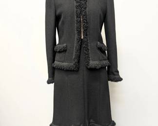 A 2003 vintage classic Chanel black boucle wool suit, the jacket and skirt both edged with a looped wool, the jacket closes at the neck with a black camellia flower button; jacket size 42 and skirt size 40.
