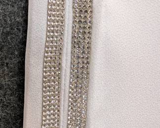Closeup of women's wide leg white trousers with crystal stripe trim