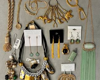 Fashion jewelry and accessories including gold-tone fashion bracelets, a statement necklace featuring black and silver woven cord with textured gold and silver leaf pendants, pair of 18KT gold-plated dangle earrings, gold-tone charm key rings, and more  