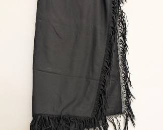 A black shawl or scarf with deeply fringed borders