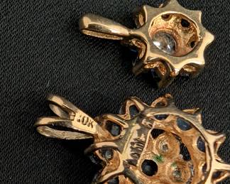 Closeup of the two different sizes 10k yellow gold sapphire and diamond pendants